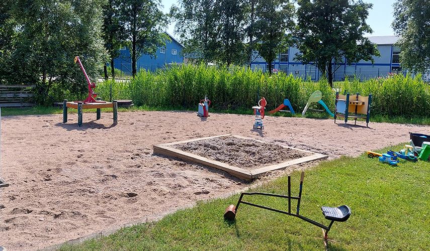 En stor lekplats med sandlåda och olika lekutrustning.