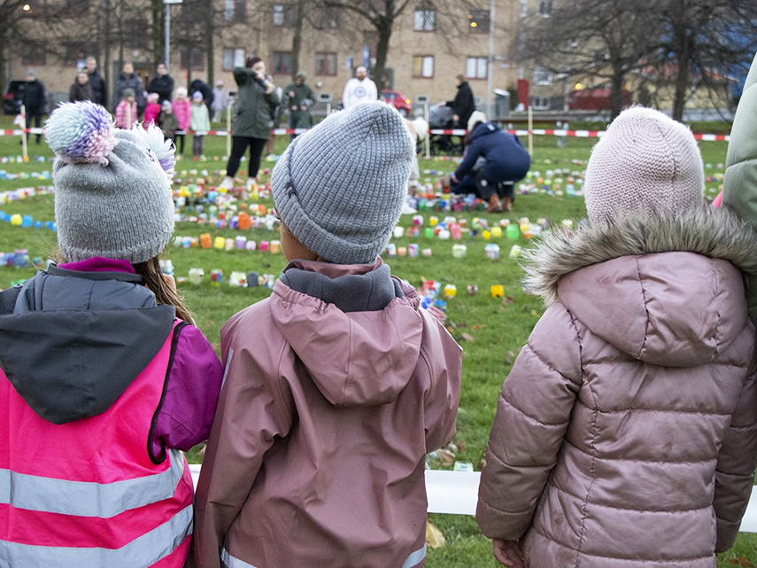 Barn står och tittar på ljusmanifestationen i Stadshusparken i Mölndal