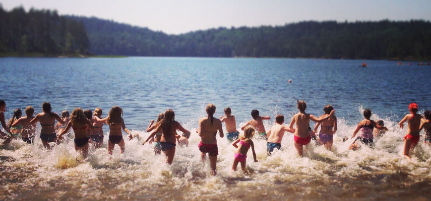 Barn och ungdomar springer ut i Djursjön en solig sommardag. Foto: Kultur- och fritidsförvaltningen