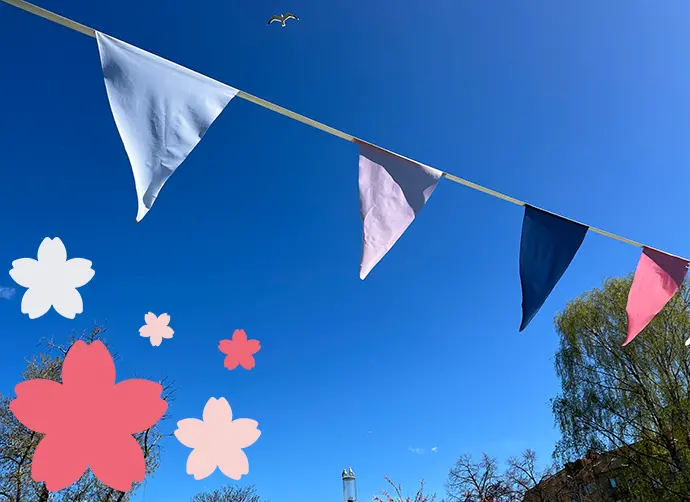Vimplar i blått och rosa mot solklar himmel. Fiskmås flyger i luften.