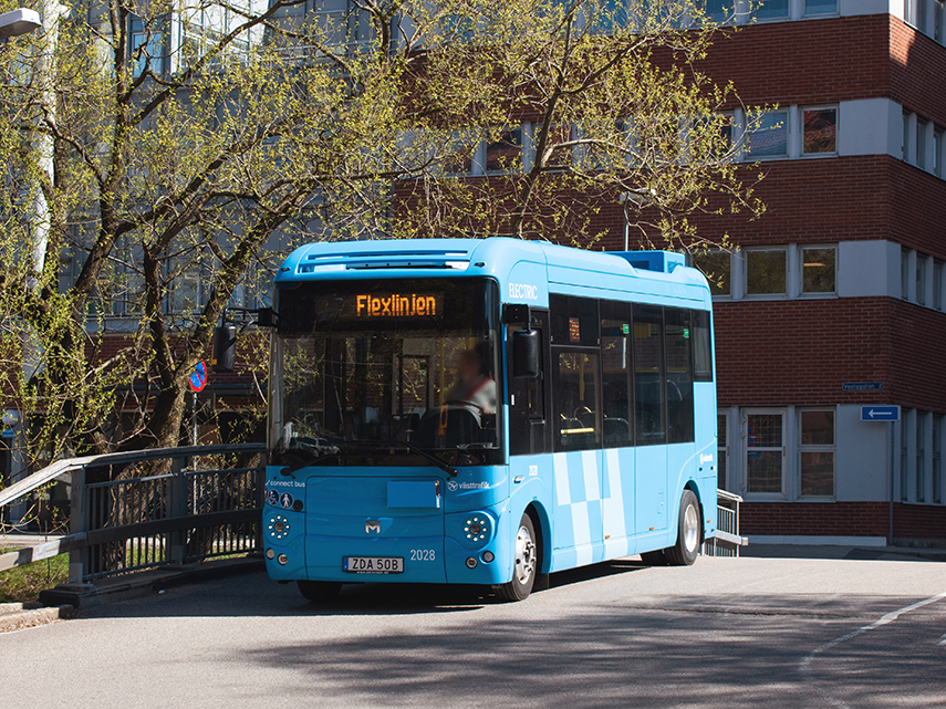 En blå mindre buss står vid korsning. Det står Flexlinjen i informationsskylten på bussen.