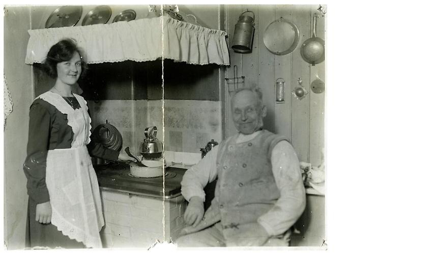 Far och dotter Johan Oskar och Helena Larsson i köket i huset Roten K3, Görjekullen/Kvarnbyn, 1920-tal. Svartvit.