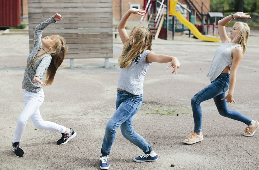 Tre flickor dansar på lekplats