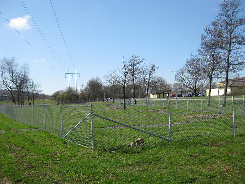 En gräsyta inhägnad med staket som en hundrastgård.