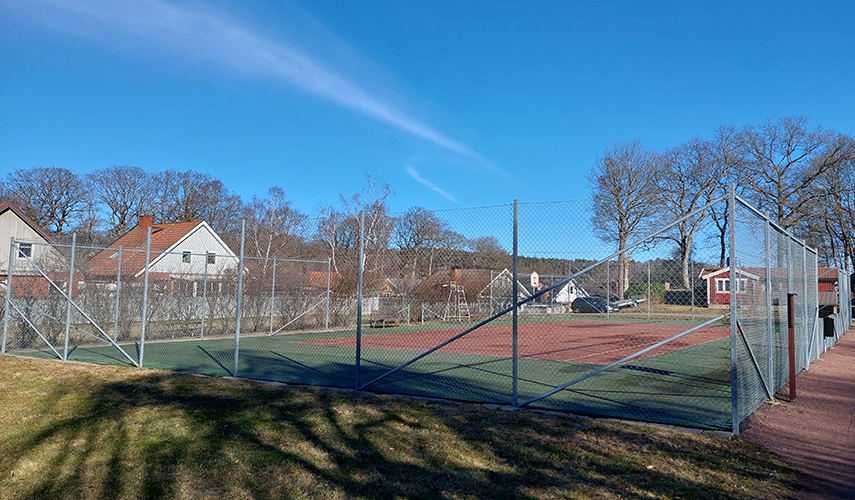 En tennisbana omgärdad av ett grönt staket.