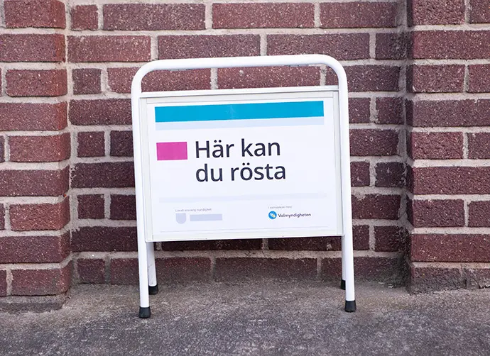 Gatupratare framför en tegelvägg med texten Här kan du rösta.