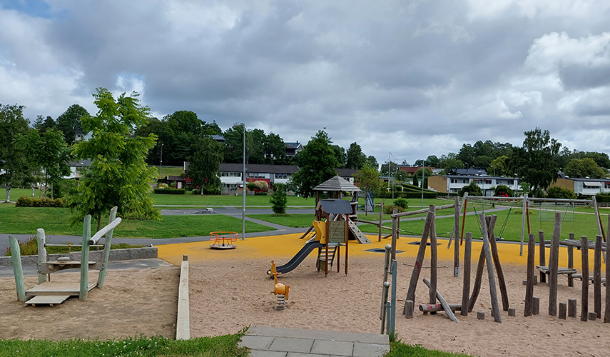 En lekplats i Valås med lekhus, rutschkana, gungor och längre bort skymtar fotbollsmål.