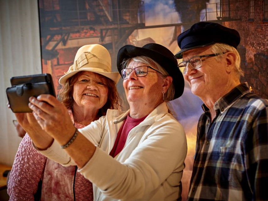 tre seniorer tar bild med telefon
