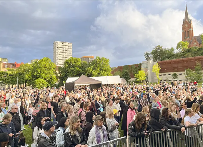 Foto från stadsfestivalen. Publikhav framför scen. Fässbergskyrkan i bakgrunden.
