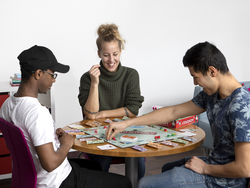 Tre personer spelar Monopol.