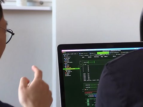 Två personer tittar på en datorskärm som visar programmeringskod.