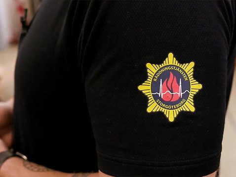 Närbild på en brandmans tröja med logotyp.