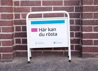 Gatupratare framför en tegelvägg med texten Här kan du rösta.